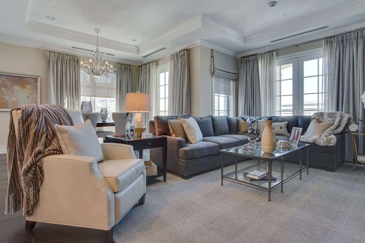 Open concept family room in Ritz-Carlton Residences, North Hills, Manhasset NY designed by Robyn B of Interiors By Just Design. Duralee sectional sofa and chair, Kravet rug, Design Master chairs, Century dining room table, custom window treatments, Visual Comfort chandelier.