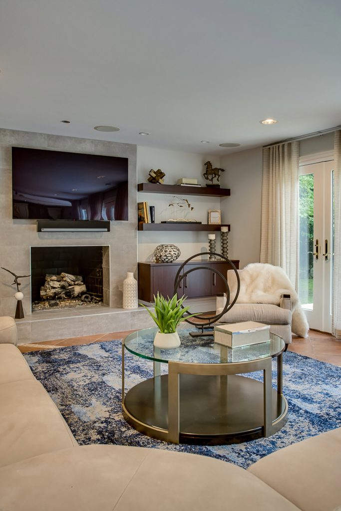 Contemporary living room with a fireplace, wall-mounted TV, and modern decor by Robyn Baumgarten.