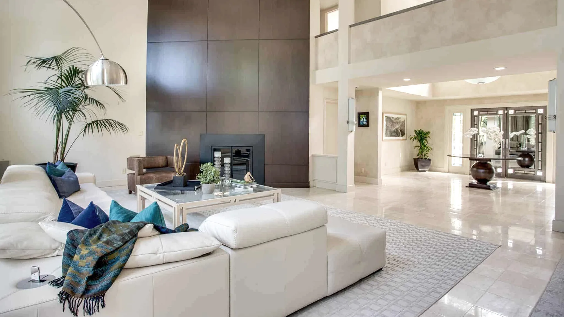 Custom wood-paneled fireplace wall spanning a double-height living room in Old Brookville