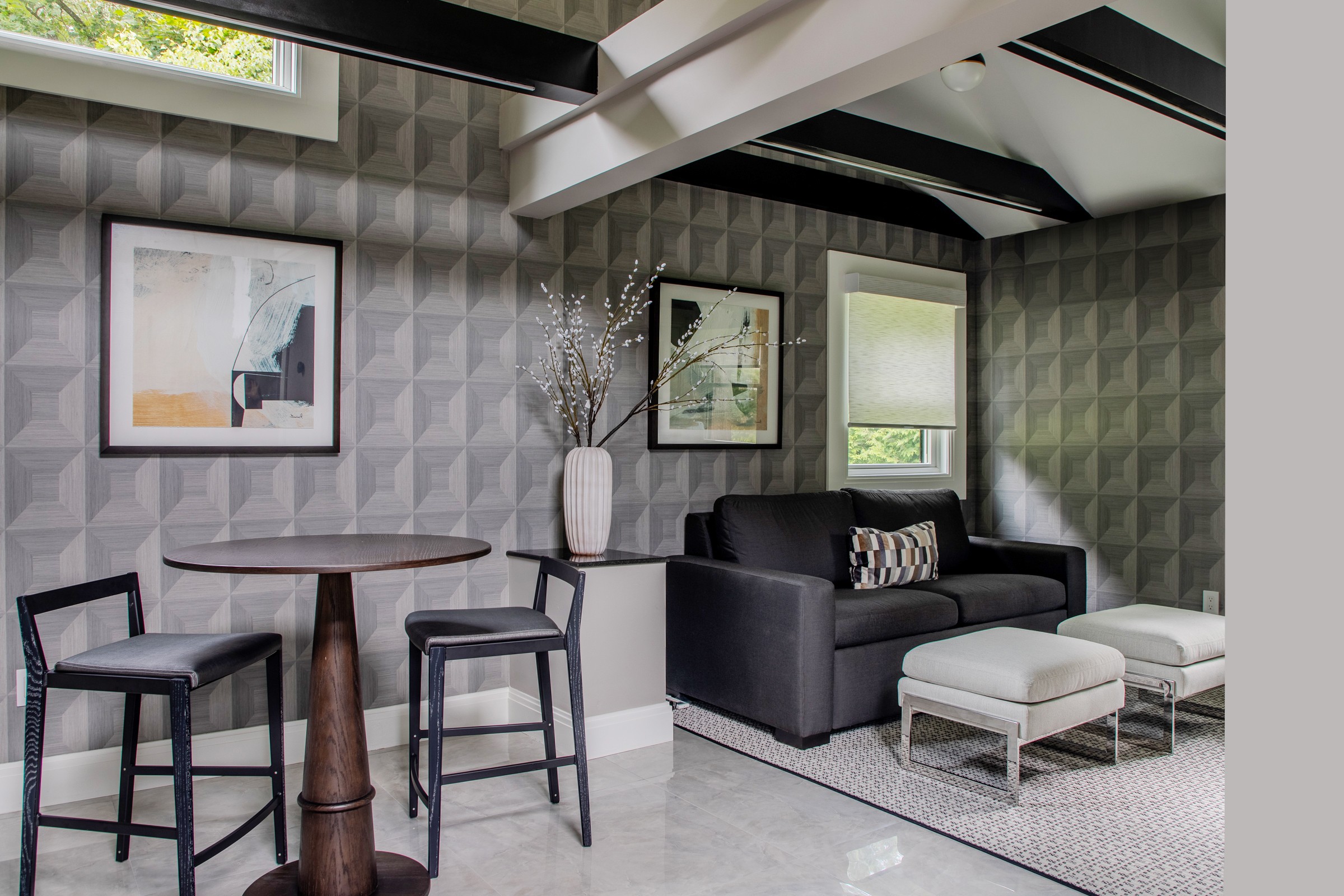 Guest house lounge with modern gray wallpaper, dark ceiling beams, and modern furniture