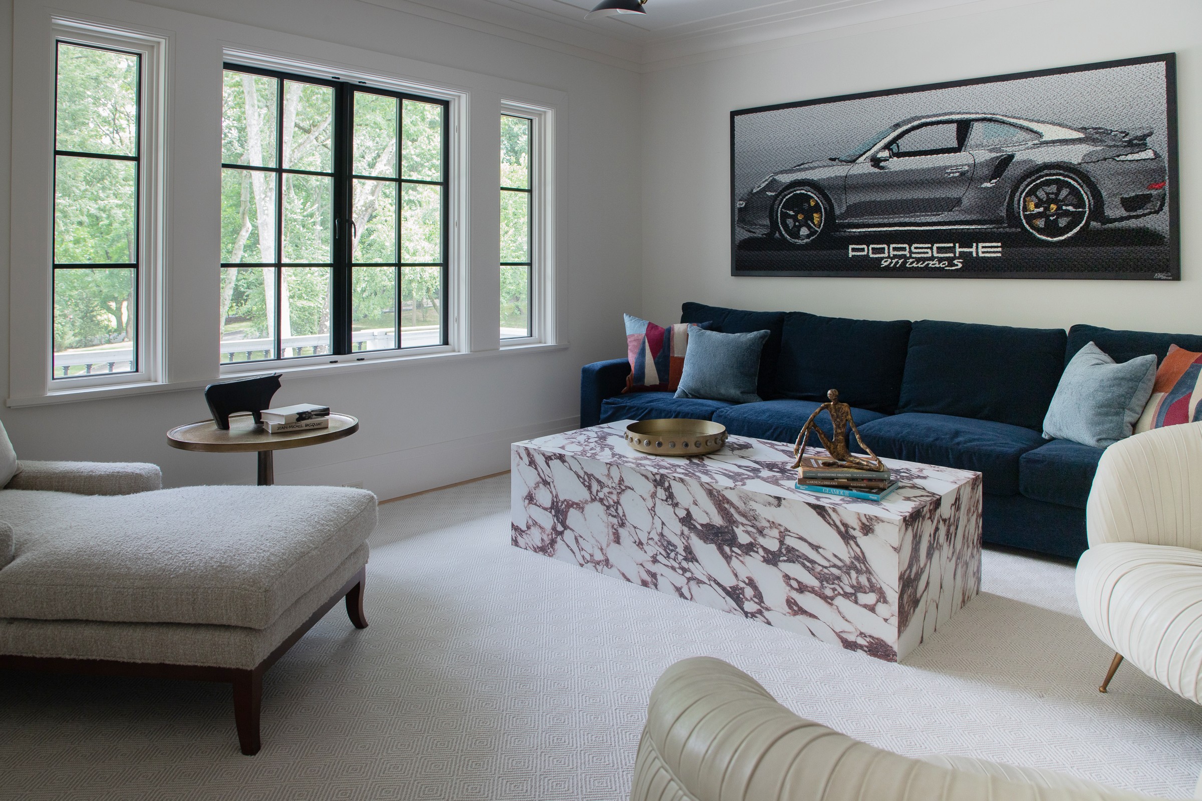 Loft with navy velvet sofa, marble block coffee table, and framed Porsche 911 Turbo S artwork