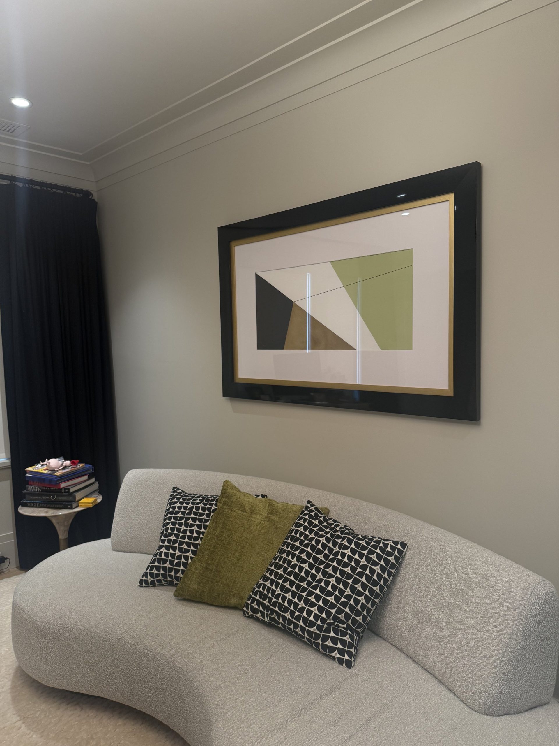 Primary bedroom sitting area with curved boucle sofa, patterned pillows, and black and gold framed geometric artwork